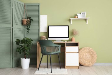 Modern bilgisayarlı ve yeşil duvarın yanındaki katlanan ekranlı çalışma alanı