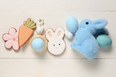 Süslü tavşan, yumurta ve beyaz ahşap arka planda Paskalya kurabiyeleri.