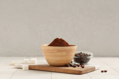 Üzerinde kahve tozu, fasulye ve şeker küpleri olan tahta.