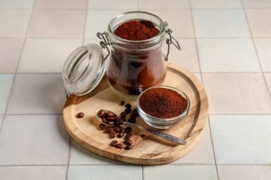 Tahta tahta tahta bir kavanoz kahve tozu, fasulye, kase ve kaşık beyaz fayansla kaplanmış.