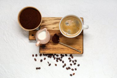 Bir fincan sütlü kahve, pudra ve fasulye beyaz arka planda.