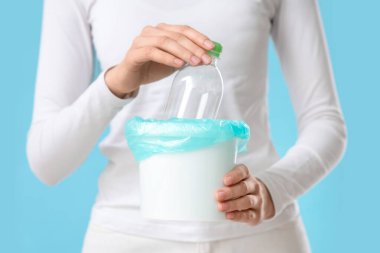 Elinde plastik kovayla mavi arka planda duran kadın, yakın plan.