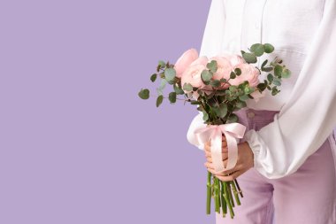 Arkaplanda bir buket ranunculus çiçeği ve okaliptüs olan genç bir kadın.