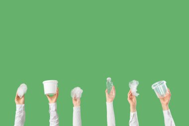 Yeşil arka planda farklı plastik parçaları olan kadın eller. Kirlilik kavramı