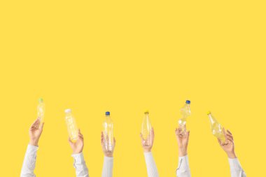 Sarı arka planda plastik şişeleri olan kadın eller. Kirlilik kavramı