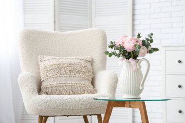 Beyaz koltuklu ve kahve masasında güzel ranunculus çiçekleri olan şık bir oturma odası.