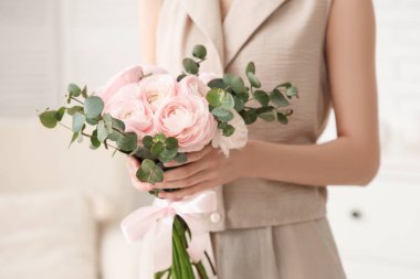 Evinde bir buket güzel ranunculus çiçeğiyle genç bir kadın, yakın plan.