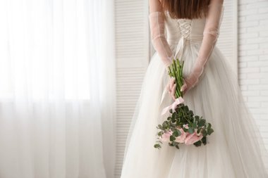 Gelinlik giymiş, evinde bir buket güzel ranunculus çiçeği olan genç bir kadın.