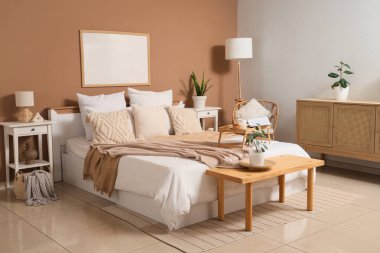 Büyük yataklı, ahşap banklı ve masalı rahat bir yatak odası.