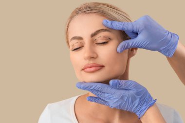 Gözlerinde izler olan genç bir kadın ve bej arka planda estetik cerrah, yakın plan. Blepharoplasty konsepti