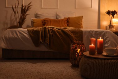 Geceleri yatak odasında yanan mumlar ve pouf üzerine çay bardağı olan tepsi.