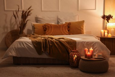 Karanlık yatak odasının içi. Parlayan lamba ve yanan mumlarla dolu.