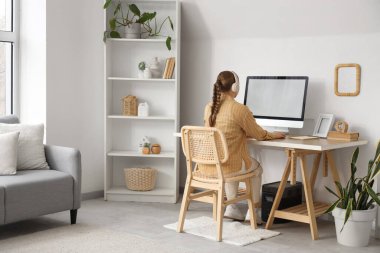 Ofisteki masada bilgisayarla çalışan genç bir kadın.