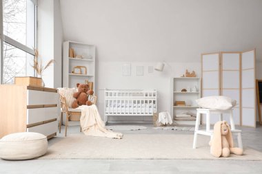 Beşiği, raf ünitesi ve oyuncakları olan çocuk odasının içinde.