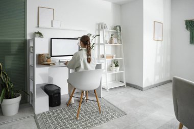 Ofisteki masada bilgisayarla çalışan genç bir kadın.