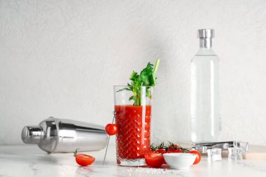 Kerevizli, domatesli, tuzlu, buzlu ve mermer masada sallanan bir bardak Bloody Mary.
