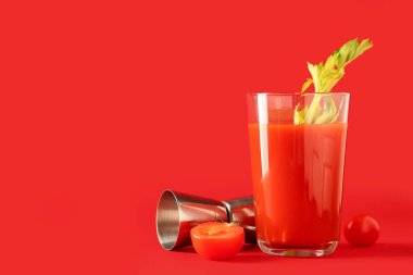 Kereviz, domates ve kırmızı arka planda ölçü kabıyla bir bardak Bloody Mary.