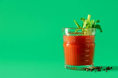 Yeşil arka planda kerevizli ve biberli Bloody Mary.