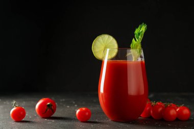 Kereviz, limon dilimi ve koyu arkaplanda domatesli bir bardak Bloody Mary.