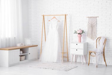 Vazo dolusu güzel ranunculus çiçeğiyle. Gelinliğin yanında. Evde askıda asılı.