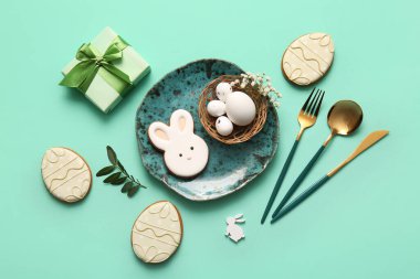 Tatlı kurabiyeler, Paskalya yumurtaları, hediye kutusu ve turkuaz arka planda çingene çiçekleri olan güzel bir masa.