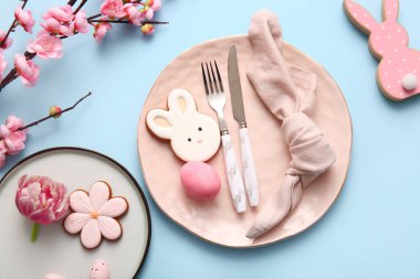 Tatlı kurabiyeler, Paskalya yumurtaları ve mavi arka planda çiçek açan dallarla dolu güzel bir masa.