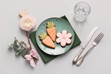 Stylish table setting with sweet cookies, beautiful flower and pussy willow branches on grey background. Easter celebration