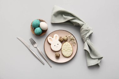 Tatlı kurabiyeler, paskalya yumurtaları ve gri arka planda çigila çiçekleri olan güzel bir masa.