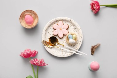 Tatlı kurabiyeli güzel masa, paskalya yumurtaları ve gri arka planda lale çiçekleri.