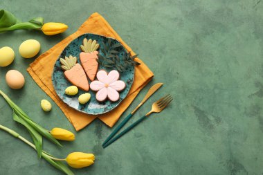 Tatlı kurabiyeler, Paskalya yumurtaları ve sarı arkaplanda sarı lale çiçekleri olan güzel bir masa.