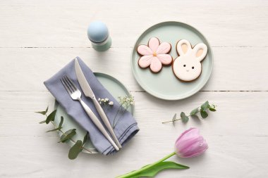 Tatlı kurabiyeli şık masa dekorları, Paskalya yumurtası, güzel çiçekler ve beyaz ahşap arka planda okaliptüs dalları.