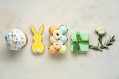 Hediye kutusu, çiçekler, paskalya yumurtaları ve bej renkli grunge arkaplanlı pasta kompozisyonu