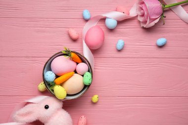 Pembe ahşap arka planda kase, dekor ve paskalya yumurtaları ile kompozisyon