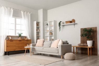 Rafa kaldırma ünitesi, puf ve gri kanepe oturma odasının içindeki beyaz duvarın yanında.