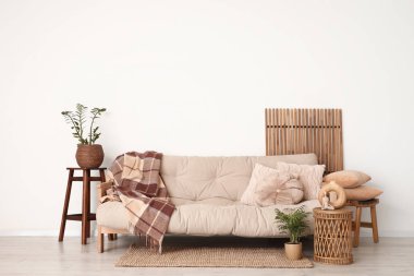 Oturma odasının iç tarafındaki beyaz duvarın yanında katlanan ekran ve gri kanepe.