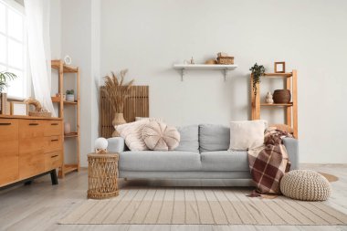 Beyaz duvarın yanında kanepe, puf ve raf üniteleri olan oturma odasının içinde.