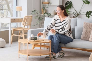 Genç bir kadın evdeki masadan spirulina hapları alıyor.