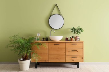 Lavabosu, kozmetik ürünleri ve aynası olan bir banyo.