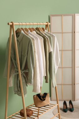 Merdivende şık kıyafetler ve odada yeşil duvarın yanında katlanmış bir ekran var.