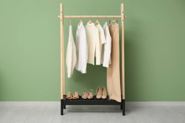 Yeşil duvarın yanında şık giysilerle dolu bir oda.