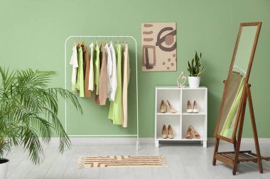 Şık kıyafetler, raf ünitesi ve yeşil duvarın yanındaki ayna ile doldur.