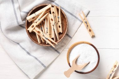 Beyaz ahşap arka planda çamaşır tozu ve mandallar.