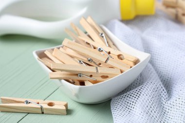 Çamaşır deterjanı ve yeşil ahşap arka planda ip torbası olan bir kase mandal.