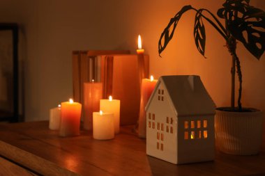 Ev şeklinde tutucu, yanan mumlar, bitki ve kitaplar karanlık odada, yakın plan