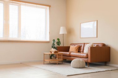 Oturma odasının içinde kahverengi kanepe, masa ve lamba var.