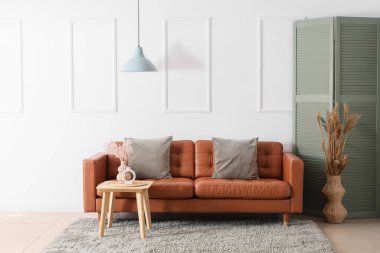 Oturma odasının içinde kahverengi kanepe, masa ve otlar var.