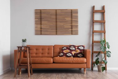 Oturma odasının içinde kahverengi kanepe, bitki ve merdiven var.