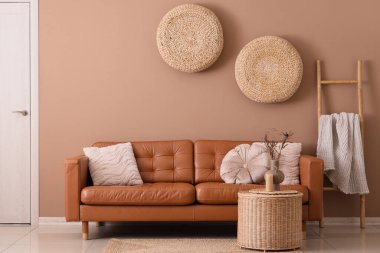 Oturma odasının içinde kahverengi kanepe, sepet ve rattan puflar var.