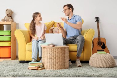 Genç kız, evdeki kanepede öğretmenle ders çalışıyor.