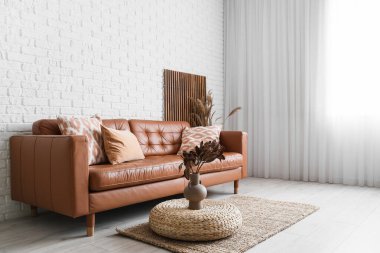 Oturma odasının içinde kahverengi kanepe ve puf.